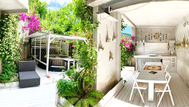 A covered outdoor patio with a dining table and chairs, surrounded by lush greenery and flowering plants. - Circeii, apartment with bedroom, living room and exterior with bathtub (San Felice Circeo)