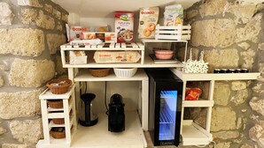 A kitchen area with stone walls, shelves stocked with bread, cereal, and other food items, a coffee maker, and a refrigerator. - Circeii, apartment with bedroom, living room and exterior with bathtub (San Felice Circeo)