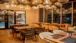 A restaurant with multiple dining tables, wicker chairs, and hanging light fixtures. - Hotel Boutique Maree (Santa Marta)