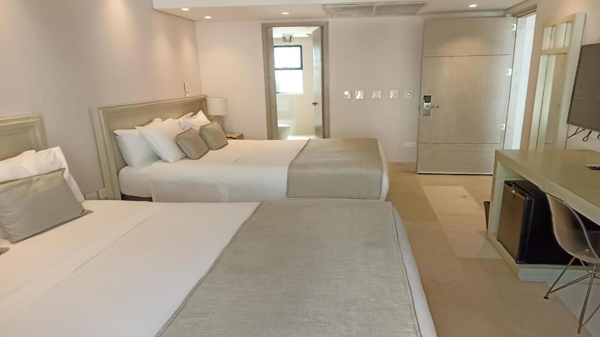 A hotel room with two beds, a desk, and a wardrobe.