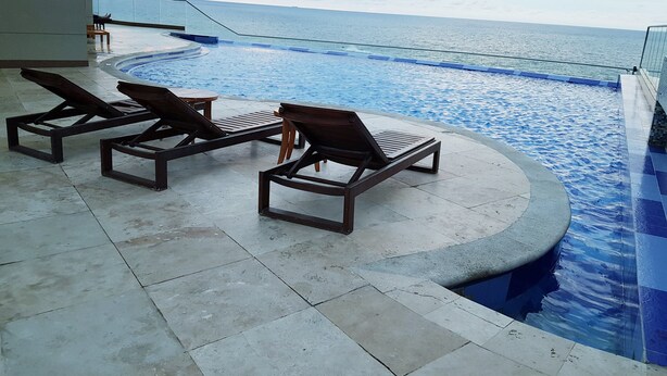Un espace aménagé au bord de la piscine, avec des chaises longues et une vue sur l’océan.