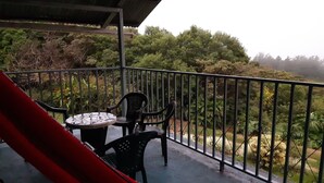 A balcony with a table and chairs, surrounded by a metal railing, overlooking a lush green landscape. - MONTEVERDE - Comfy, well-equipped House in woods with spectacular view! (Santa Elena)