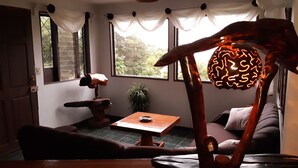 A room with a wooden table, a sofa, and a decorative sculpture. - MONTEVERDE - Comfy, well-equipped House in woods with spectacular view! (Santa Elena)