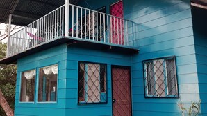 A blue building with a balcony, a red door, and windows with metal grilles. - MONTEVERDE - Comfy, well-equipped House in woods with spectacular view! (Santa Elena)