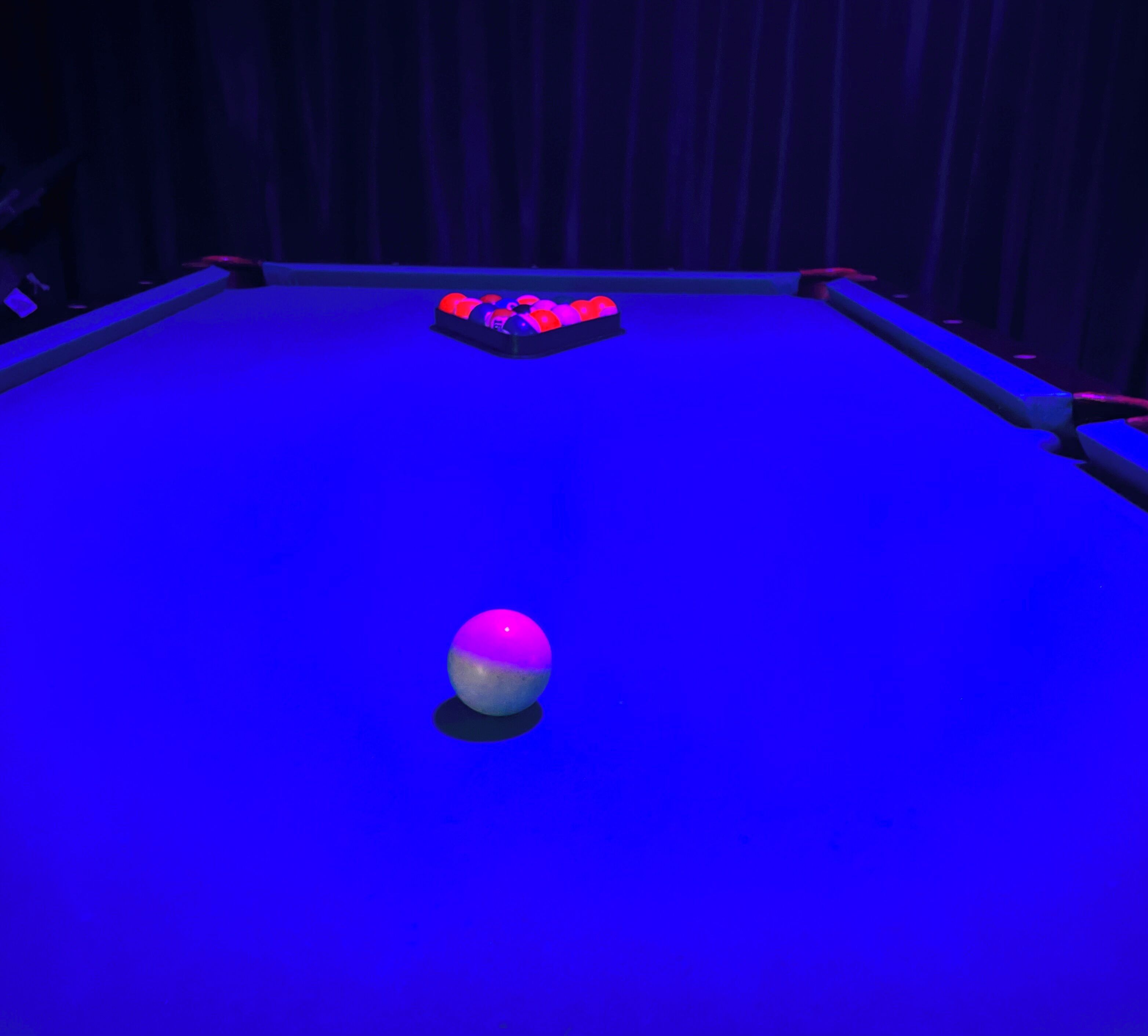A blue-lit room with a single spherical object on the floor.