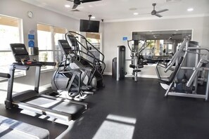 Un gimnasio con cintas de correr, elípticas y equipo de pesas.