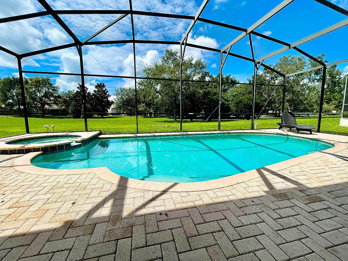 Une piscine extérieure couverte, dotée d’un patio en briques et d’une structure de toit en métal.
