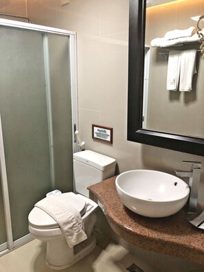 A bathroom with a toilet, a sink, a shower, and a towel rack. - Royale Tagaytay B&B (Alfonso)