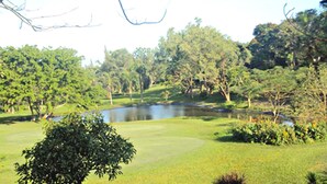 A golf course with a pond, surrounded by lush greenery and trees. - Royale Tagaytay B&B (Alfonso)