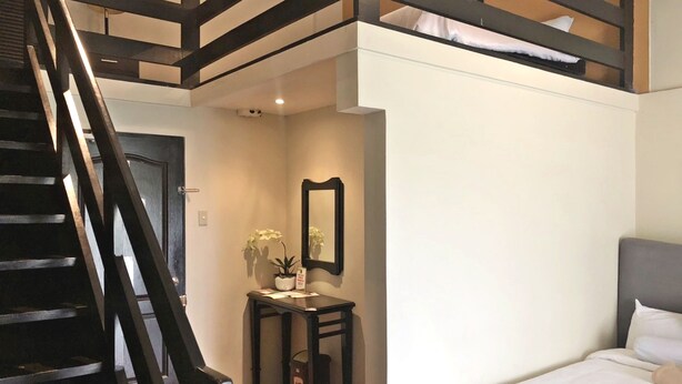 A bedroom with a bunk bed, a bedside table with a mirror, and a potted plant. - Royale Tagaytay B&B (Alfonso)