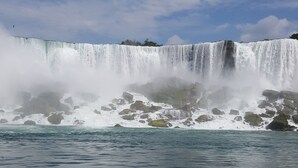 Une grande cascade où l’eau dévale les rochers et se jette dans un plan d’eau.