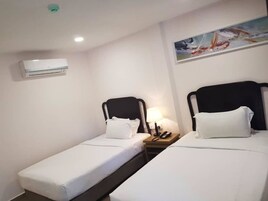 A hotel room with two single beds, a nightstand with a lamp, and a painting on the wall.