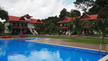 Un hotel con piscina, edificios de techo rojo y palmeras.