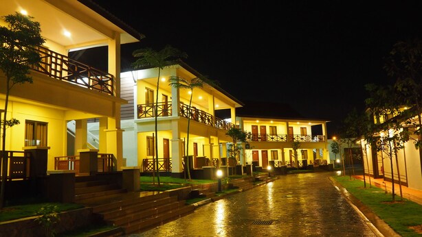 A multi-story hotel with balconies, a wet ground, and well-lit windows. - Lotus Seaview Beach Resort (Bandar Penawar)