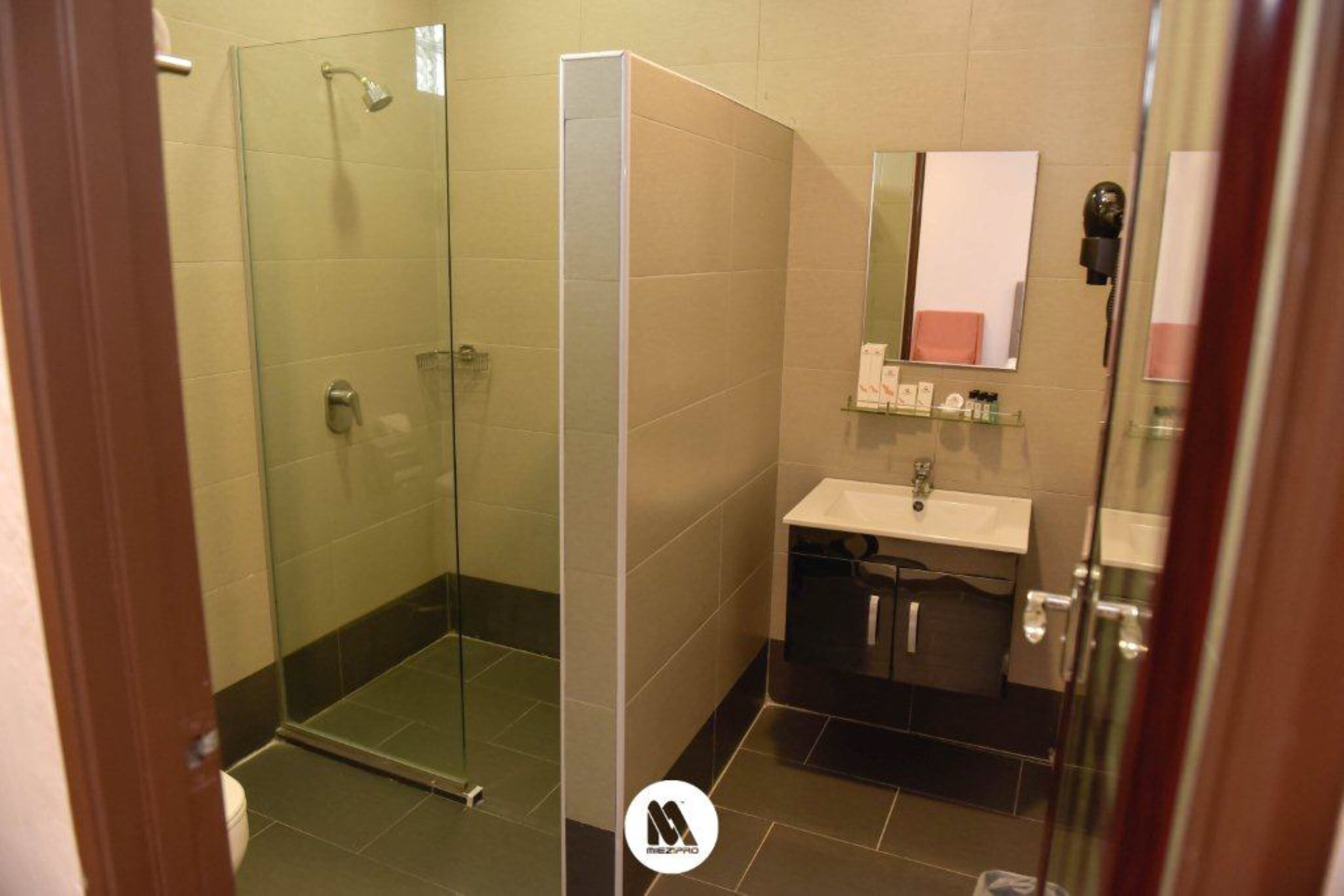 A modern bathroom with a glass shower enclosure, a sink with a mirror, and a small shelf with toiletries.