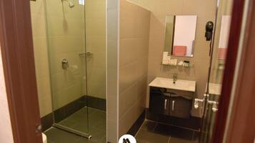 A modern bathroom with a glass shower enclosure, a sink with a mirror, and a small shelf with toiletries.