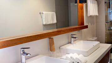 Un baño moderno con dos lavamanos, un espejo grande y una zona de ducha.