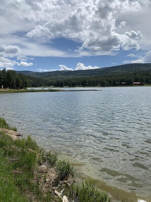 A lake with a wooden dock, surrounded by grassy areas and trees. - Mountain Retreat: 5 min walk to lake & hiking and 4 min drive to golf & slopes.  (Angel Fire)