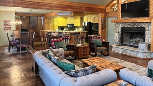 Una sala de estar acogedora con chimenea, un comedor y una cocina con gabinetes amarillos.