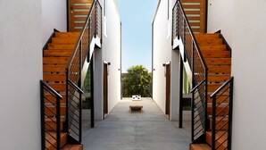 A corridor with wooden stairs and metal railings, leading to a bench and a door at the end. - Avalon 2 Unit Buyout (I & III) AvantStay | Mins to Gaslamp| Beautiful Deck w/BBQ (San Diego)