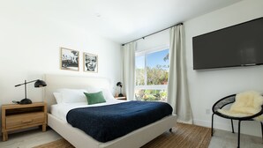 A modern bedroom with a bed, a nightstand, a chair, a TV, and a window with curtains. - Avalon 2 Unit Buyout (I & III) AvantStay | Mins to Gaslamp| Beautiful Deck w/BBQ (San Diego)