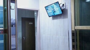 A hallway with a closed door and a mounted security monitor on the wall. - Hub Guest House (Incheon)