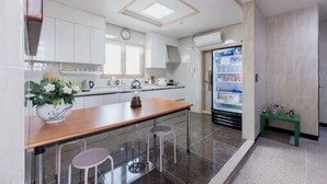 A modern kitchen with white cabinets, a wooden countertop, and a refrigerator. - Hub Guest House (Incheon)