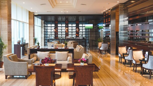 A modern hotel lobby with a seating area, a reception desk, and a wall-mounted television. - Swiss-Belhotel Serpong (South Tangerang)