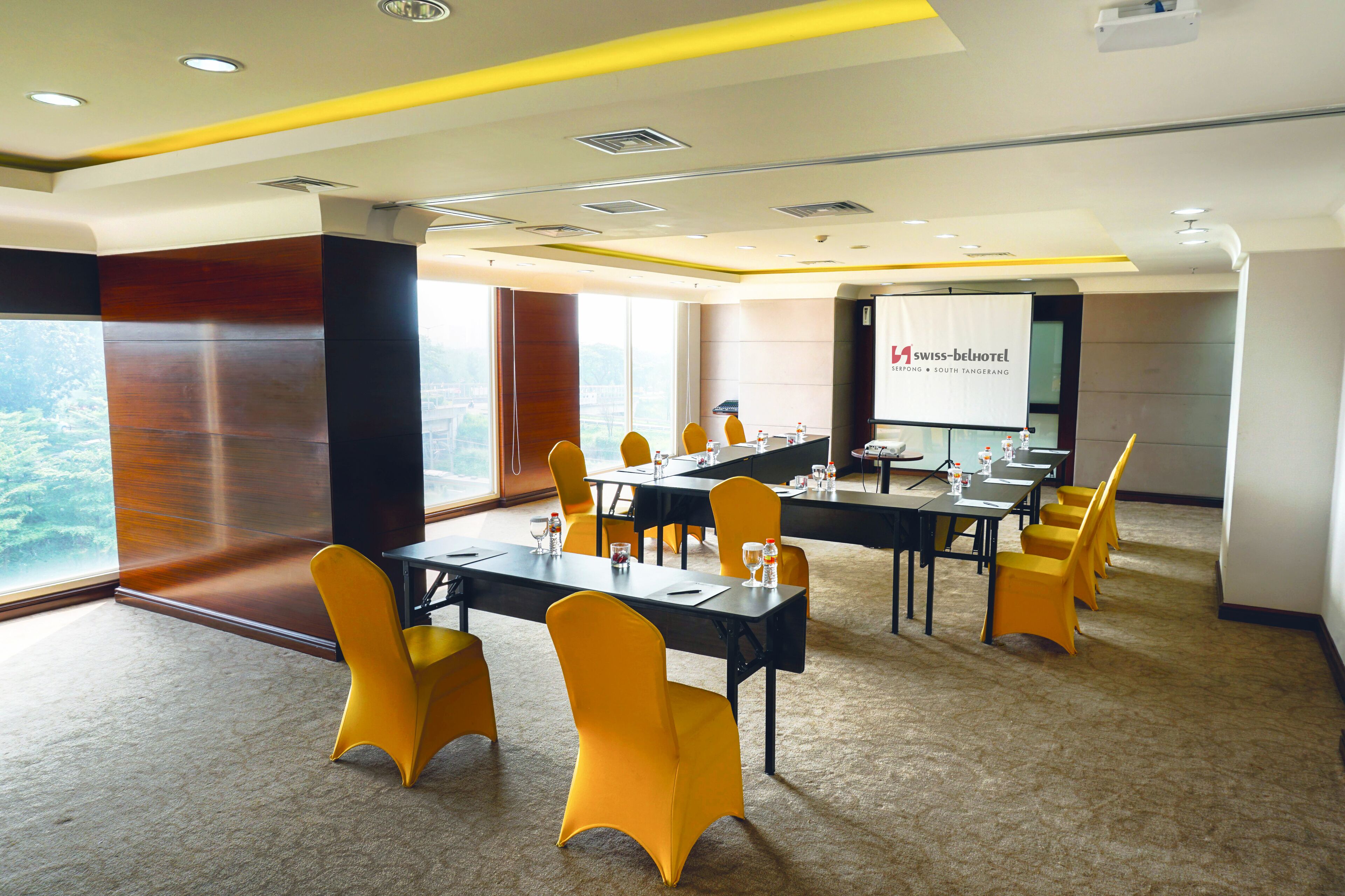 A conference room with a large table, yellow chairs, and a presentation screen.
