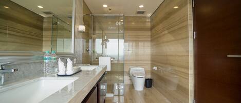 Un baño moderno con encimera de mármol, cabina de ducha de vidrio y puerta de madera.