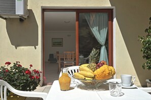 Enjoy a meal al fresco at this outdoor dining area, complete with a table set for a meal and a refreshing fruit bowl.