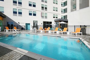 A swimming pool with lounge chairs and a building in the background.