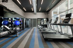 Academia com esteiras, bolas de exercício e aparelhos de musculação.