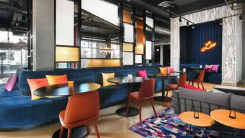 Een moderne lounge met zitplaatsen, tafels en een neonbord.