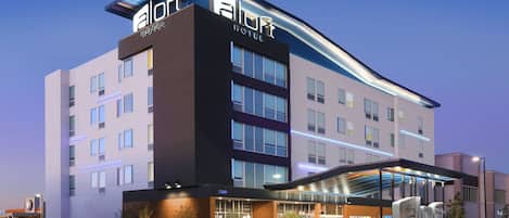 A hotel with a modern design, featuring a prominent 'aloft' sign on the facade.