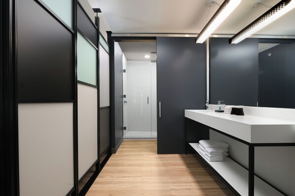 A modern bathroom with a large mirror, white sink, and a shower area.