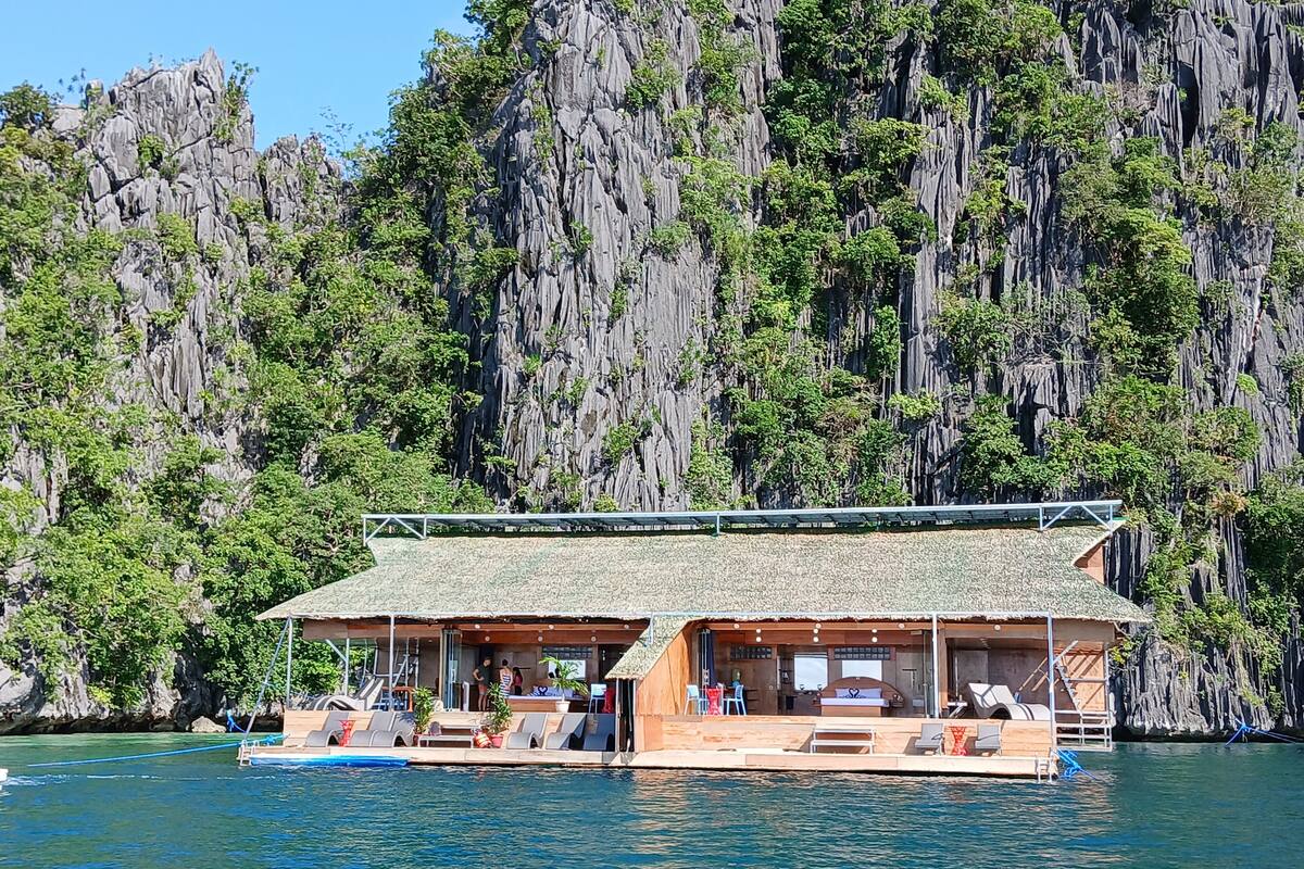 Una casa flotante con techo de paja, varias habitaciones y una pequeña terraza.
