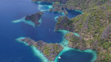 An aerial view of a coastal area with multiple small islands surrounded by clear blue waters and lush green vegetation.