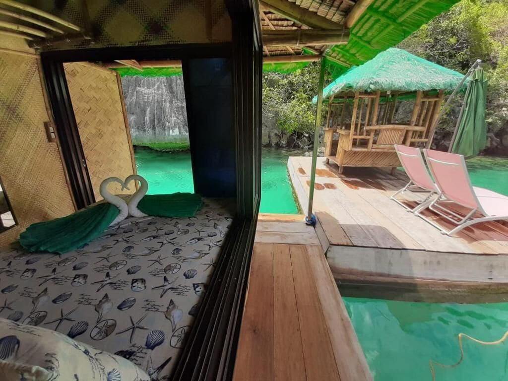 A room with a bed, a small pool, and a wooden deck with lounge chairs.