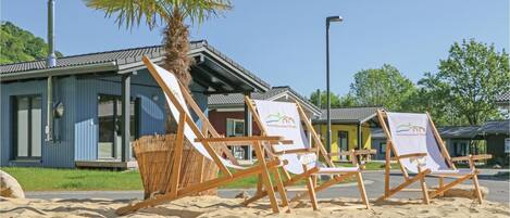 Des chaises de plage avec une banderole, un palmier et un bâtiment doté d’un toit en tuiles.