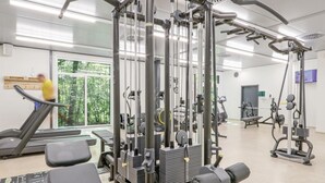 A gym with various exercise machines, a treadmill, and a large window with a view of trees. - Stunning home in Thale with sauna (Thale)