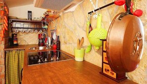 A kitchen with a wooden countertop, a hanging pot rack, and various kitchen utensils.