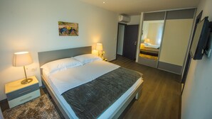 A hotel room with a bed, bedside lamps, a nightstand, a painting on the wall, a wardrobe, and a mirror. - LUXURY 7 BEDROOM VILLA  WITH PRIVATE POOL,TENNIS COURT,GYM AND SPA (Donji Proložac)