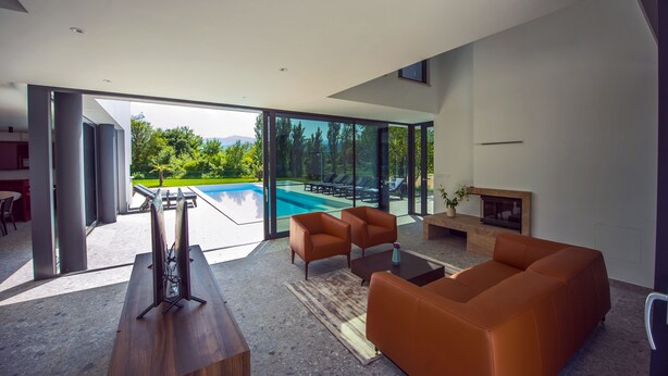 A modern living room with a large glass door leading to a pool area, a sofa, a coffee table, and a fireplace. - LUXURY 7 BEDROOM VILLA  WITH PRIVATE POOL,TENNIS COURT,GYM AND SPA (Donji Proložac)