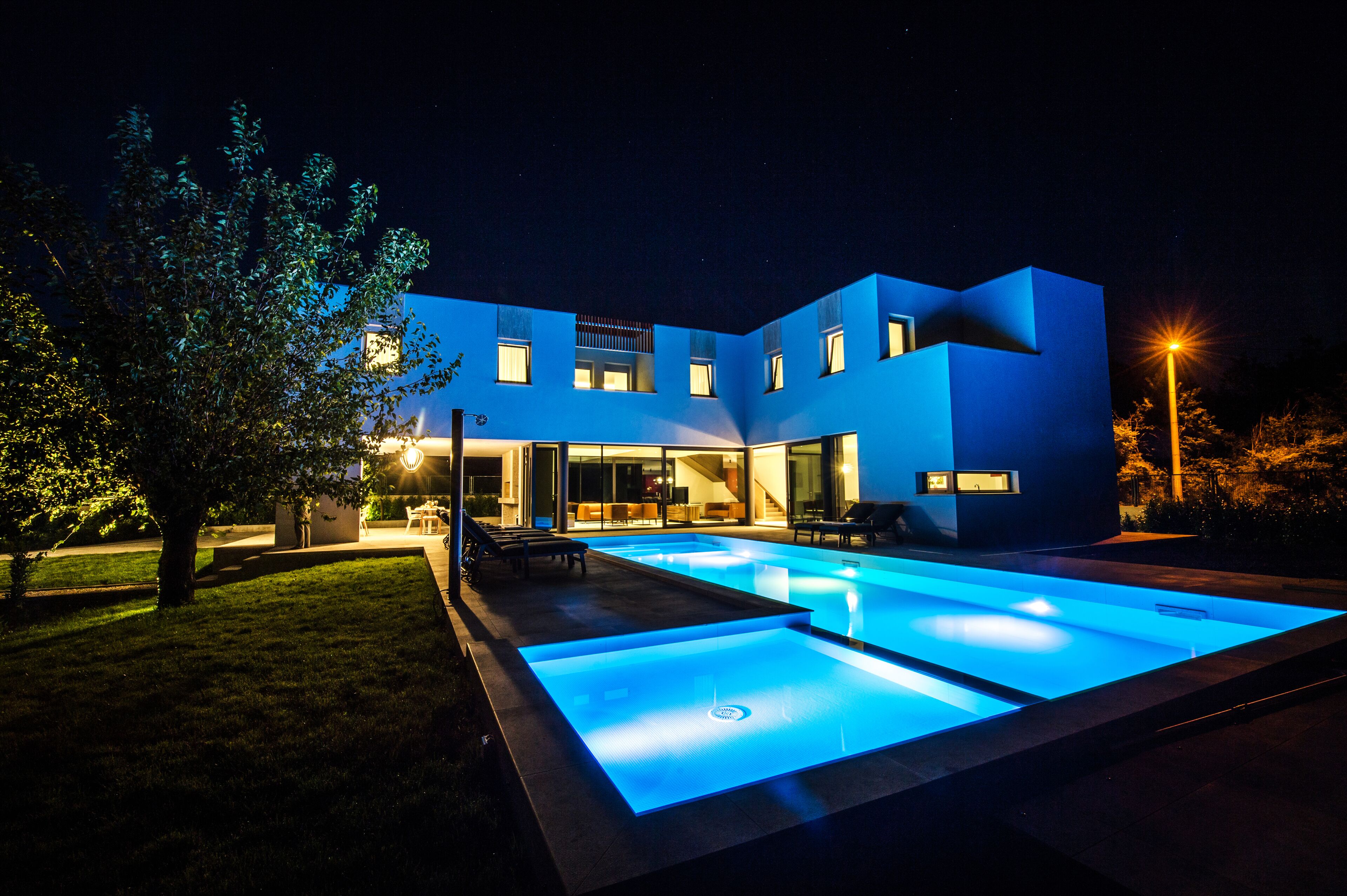 A modern house with a swimming pool at night.