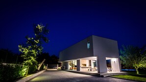A modern house with a large glass facade, a flat roof, and a well-lit outdoor area. - LUXURY 7 BEDROOM VILLA  WITH PRIVATE POOL,TENNIS COURT,GYM AND SPA (Donji Proložac)