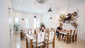 A dining area with multiple tables and chairs, a potted plant, and a decorative wall arrangement.