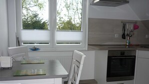 Una cocina con una mesa de comedor, sillas, una ventana con persianas, estufa y un lavabo.