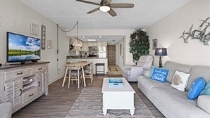 Ein Wohnzimmer mit Fernseher, Deckenventilator, Sofa und Couchtisch.