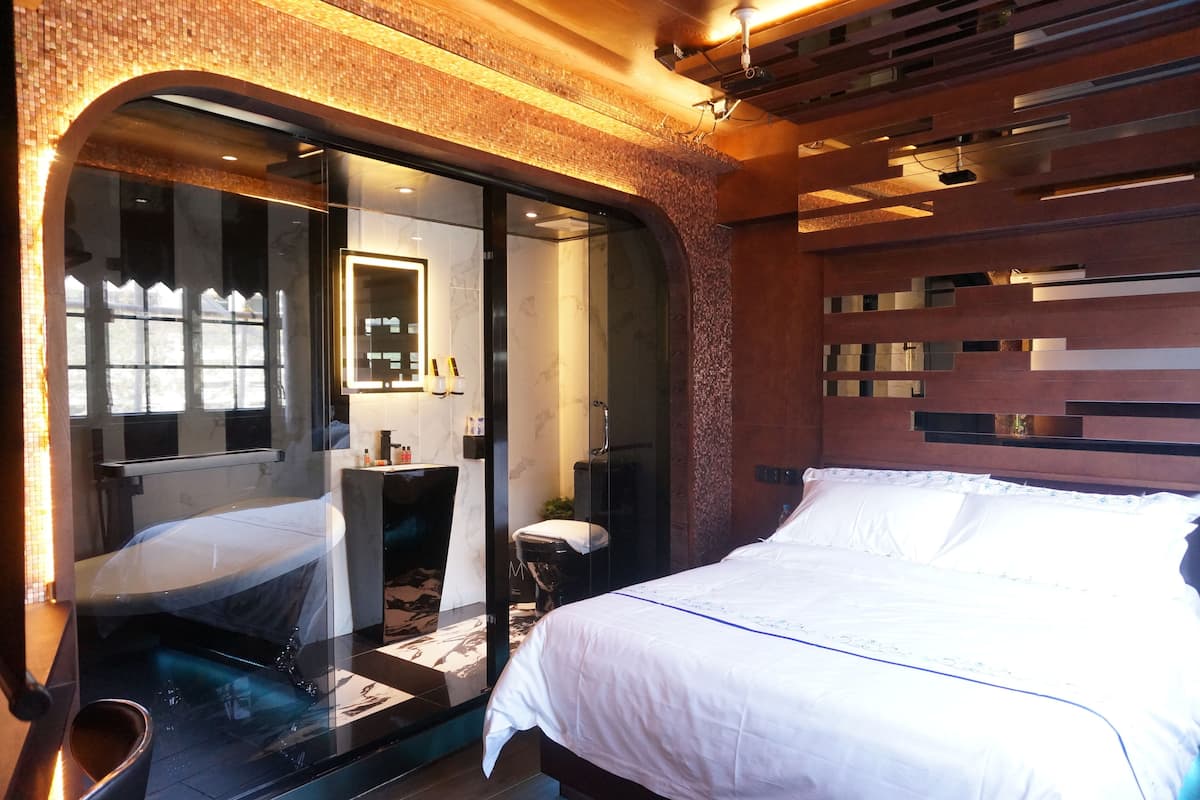 Une chambre d’hôtel moderne dotée d’un grand lit, d’une douche en verre et d’une coiffeuse avec un miroir.